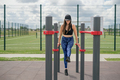 A woman does sports on crossbar on a sports field. Workouts aimed at press. - PhotoDune Item for Sale