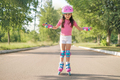 Preschool girl in protective  helmet and roller skates rides on asphalt path - PhotoDune Item for Sale