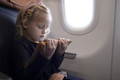 Focused girl watching video on tablet in plane - PhotoDune Item for Sale
