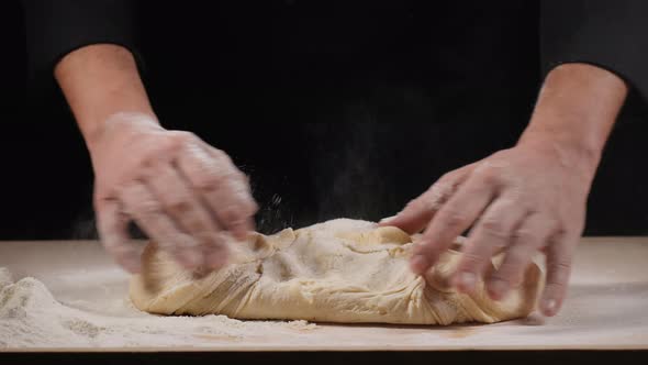 Hands of Baker Kneading Dough Isolated on Black Background