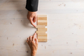 Male and female hands pushing two blank wooden pegs into a stack of them - PhotoDune Item for Sale