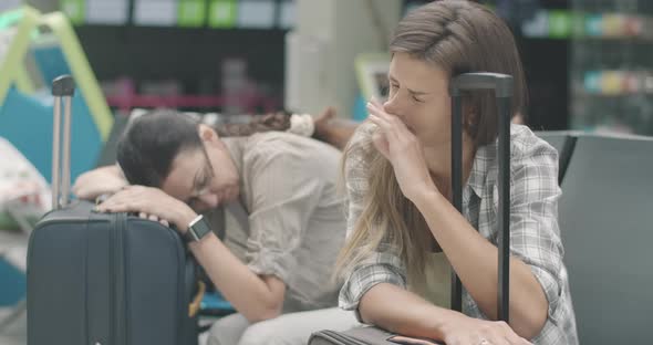 Exhausted Young Woman Sleeping on Travel Bag As Mid-adult Lady Sleep at the Background on Suitcase