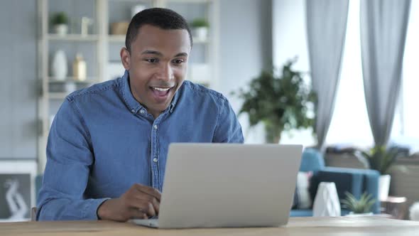 Excited Young African Man Celebrating Success Working on Laptop