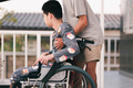 Teenager boy on wheelchair in the outdoor activity, Family Caregiving and diverse family concept. - PhotoDune Item for Sale