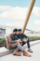 Two young businessman sitting outdoors sharing and using tablet - PhotoDune Item for Sale