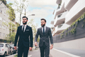 Two young elegant businessmen walking outdoors discussing and chatting - PhotoDune Item for Sale