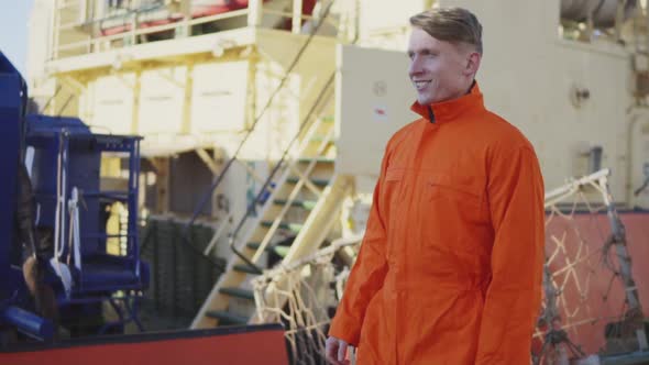 Harbor Worker in Orange Uniform is Walking on Cargo Harbor Site