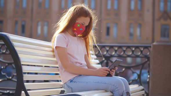 Cute Preteen Girl in Medical Mask Sitting on Street Bench with Digital Tablet