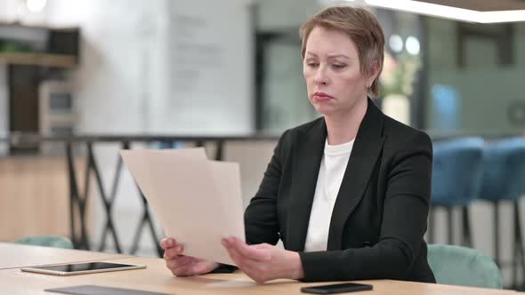 Disappointed Old Businesswoman Reading Documents in Office