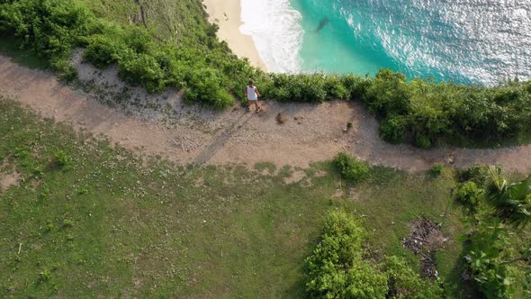 Tourist admiring sea view from the cliff, aerial shot revealing famous Kelingking Beach, Nusa Penida