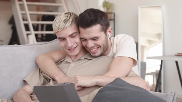 Homosexual Couple Hugging and Watching Film Using Tablet