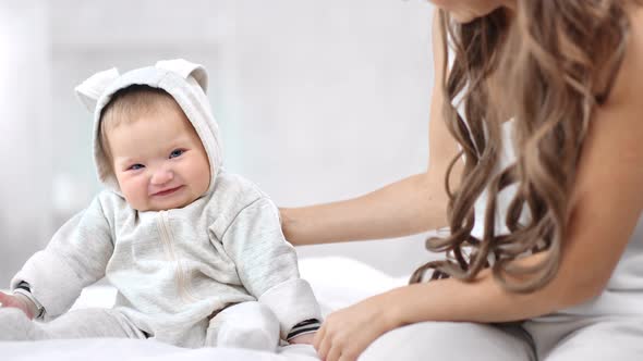 Smiling Baby Wearing Cute Overall Sitting on Bed Having Positive Emotion Looking at Camera