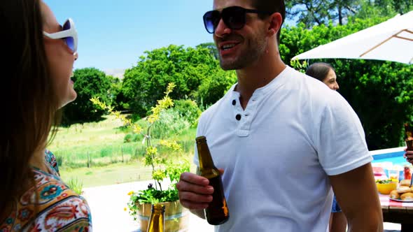 Couple interacting while having a bottle of beer near poolside