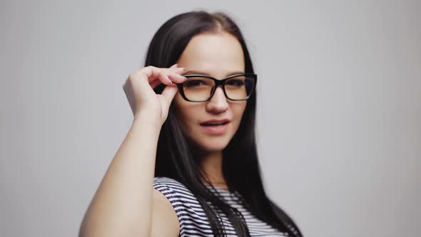 Attractive young woman in stylish eyeglasses removes them to the camera close-up.
