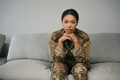 Beautiful woman in camouflage clothes is sitting on soft sofa - PhotoDune Item for Sale