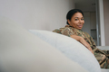 Happy african american military woman is sitting in bright living room - PhotoDune Item for Sale