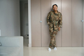 Happy military woman stands in a cozy living room - PhotoDune Item for Sale