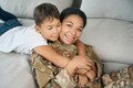Boy hugs his mother by neck, they are located on sofa - PhotoDune Item for Sale