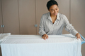 Pleasant african american maid hangs a white sheet to dry - PhotoDune Item for Sale