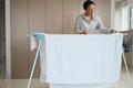 Pretty african american woman is hanging white sheet to dry - PhotoDune Item for Sale