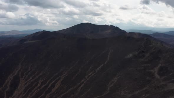 Aerial View of the Mountain Against the Background of Clouds and a Mountain Range