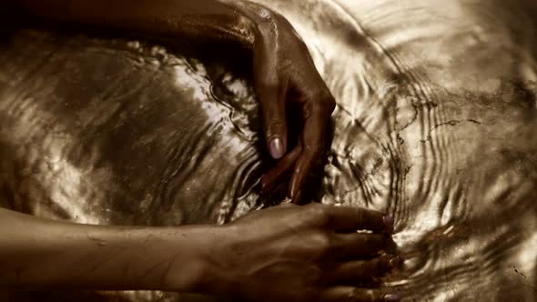 Female Hands is Stroking Melted Gold Closeup of Golden Palms of Woman in Water