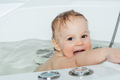 A small smiling beautiful baby bathes in a white bath, cheerful photography. - PhotoDune Item for Sale
