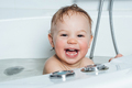 A small smiling beautiful baby bathes in a white bath. Cheerful photography - PhotoDune Item for Sale