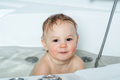 A small smiling beautiful baby bathes in a white bath, cheerful photography - PhotoDune Item for Sale