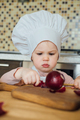 Little girl cooking in the kitchen wearing an apron and a Chef's hat. - PhotoDune Item for Sale