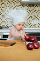 Little girl cooking in the kitchen wearing an apron and a Chef's hat - PhotoDune Item for Sale