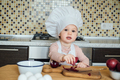 Little girl cooking in the kitchen wearing an apron and a chef's hat - PhotoDune Item for Sale