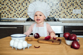 Little girl cooking in the kitchen wearing an apron and a chef's hat. - PhotoDune Item for Sale