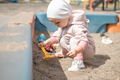 A small Child alone plays in a sandbox on the playground in the yard. - PhotoDune Item for Sale