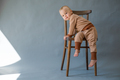 Portrait cute one year old baby girl, wearing brown suit, sitting on a wooden chair. - PhotoDune Item for Sale