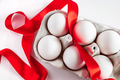 Easter eggs in a cardboard box with a red festive ribbon on a white background. - PhotoDune Item for Sale