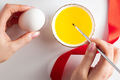 Young woman draws with colorful paints on white eggs for Easter. - PhotoDune Item for Sale