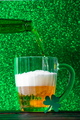 Beer is pouring into a mug on a green background.  - PhotoDune Item for Sale