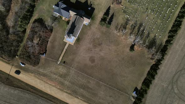 Top-down aerial view from high above showing black car driving along a dusty dirt road and passing S