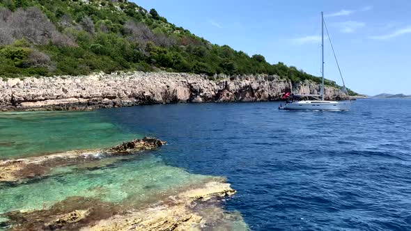 Sailboat is heading towards the sea. Green and blue water at the coast of Sali Dugi Otok Croatia 4K