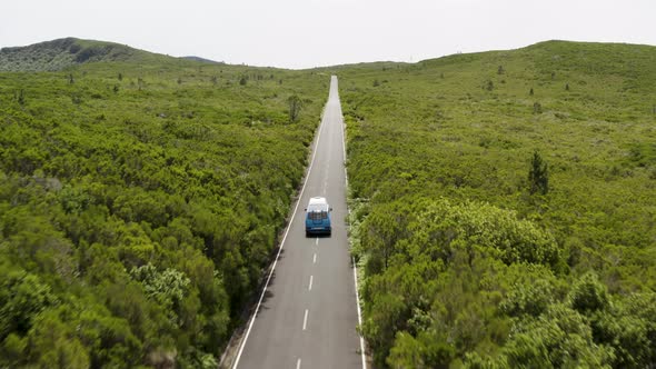 Beautiful aerial shot following a VW-Camper van on a scenic road during daytime on Madeira, Portugal