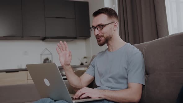 Concentrated 30s Man Sitting on Sofa in Living Room Looking at Computer Screen Involved in Online