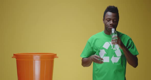 Young Man Throwing Plastic Bottle To Recycle Bin