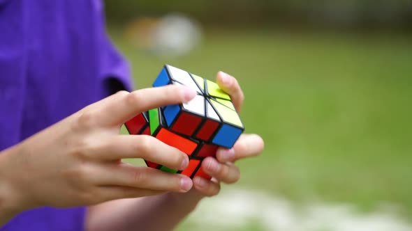 Close-up video of solving Rubik's cube. Hands of a boy shows quick combination of Rubik's cube