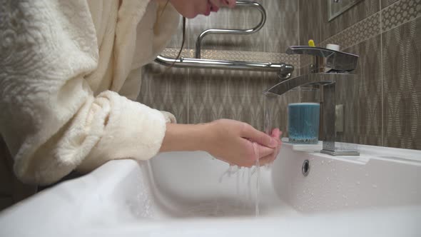 A Caucasian Beautiful Woman Washes Her Face Under Running Water in a Home Bathroom