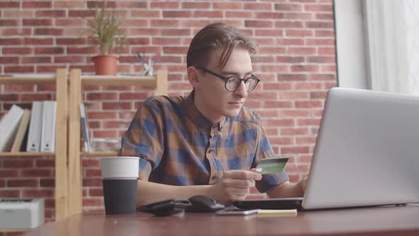 The Guy Enters the Bank Card Data Into the Laptop, A Hipster Prints a Credit Card Number in a Laptop