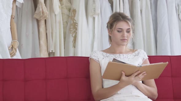 Bride Reading Book or Catalogue in Wedding Studio