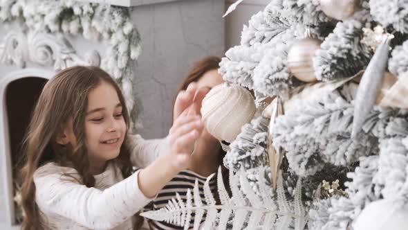 Joyful Young Attractive Beautiful Woman and Little Girl Decorate a Christmas Tree