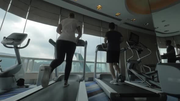 In Hong Kong, China in gym on treadmills running young woman and man