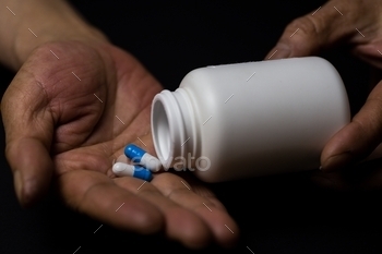 Closeup shot of a person taking medicine capsules out of the box